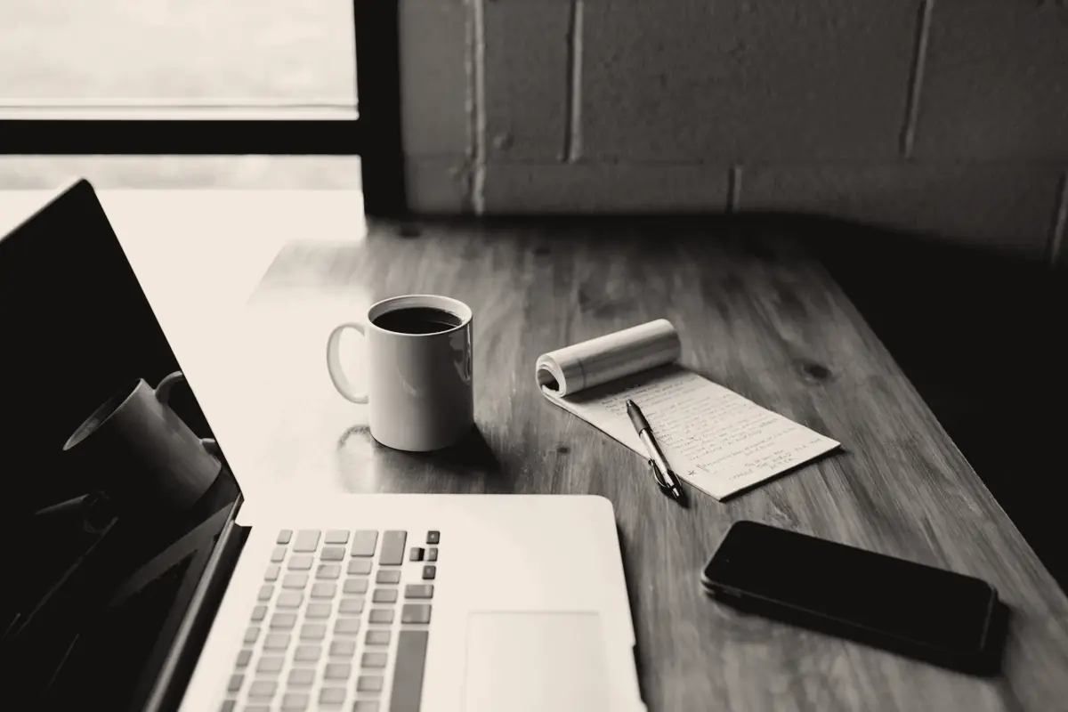 Il tavolo della redazione: portatile, quaderno degli appunti, telefono di prova e caffè